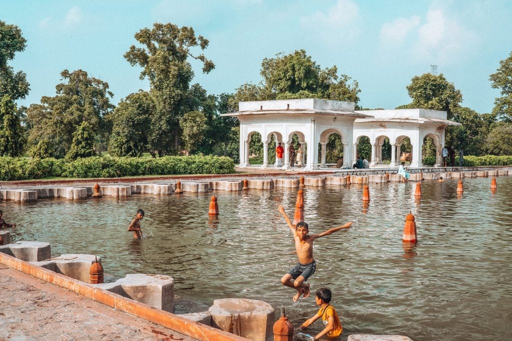 children playing and swimming inside a garden pool called shalimar bagh in lahore pakistan
