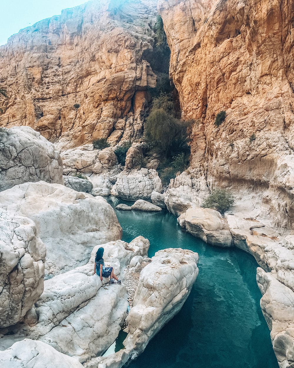 girl sitting on rock in wadi bani khalid in oman