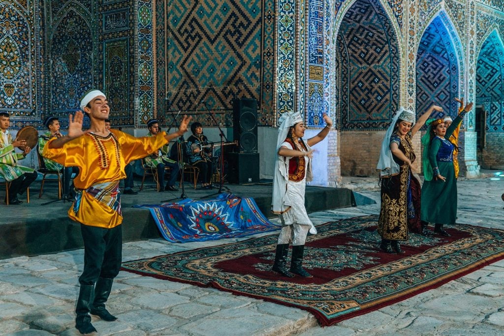dancers performing in concert in front of madrasah tile work in registan square uzbekistan at night