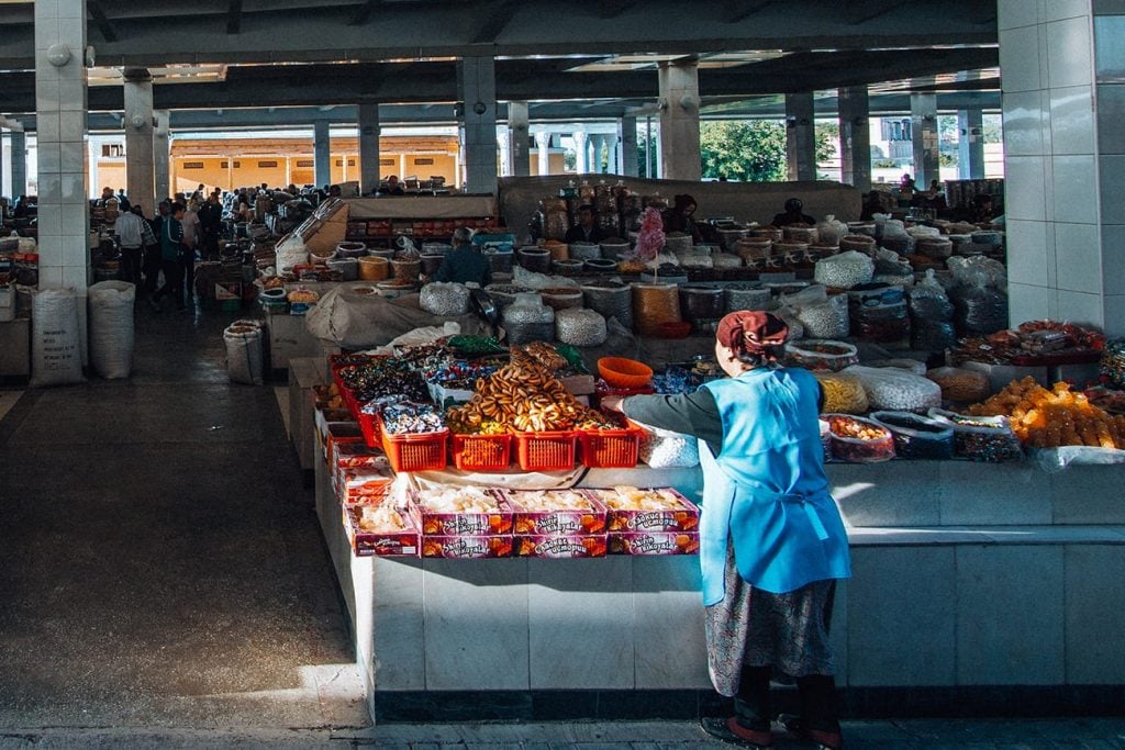 local uzbek lady standing next to spices in bazaar uzbekistan