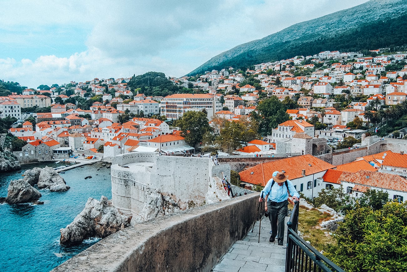 man walking by houses with red roofs in dubrovnik croatia