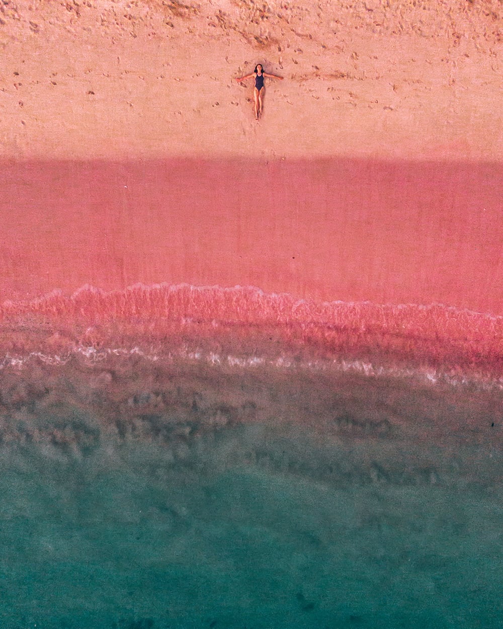 girl lying on the pink beach in komodo island indonesia