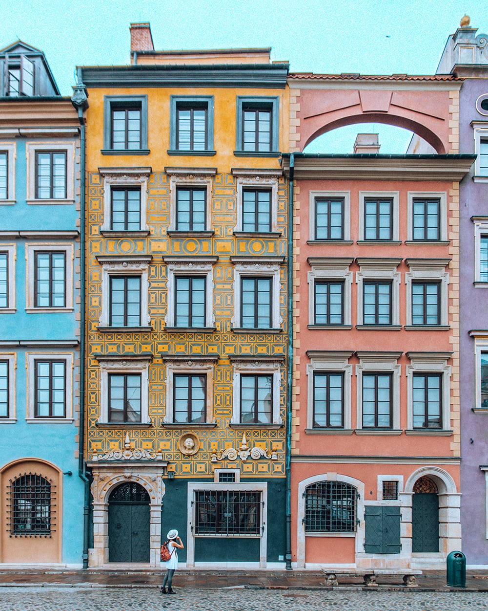 girl standing in front of colorful buildings in the old town of warsaw poland