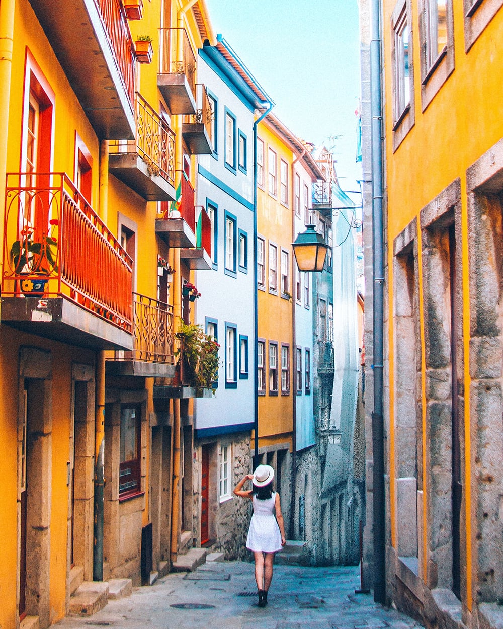 a girl walking amongst yellow buildings in porto portugal