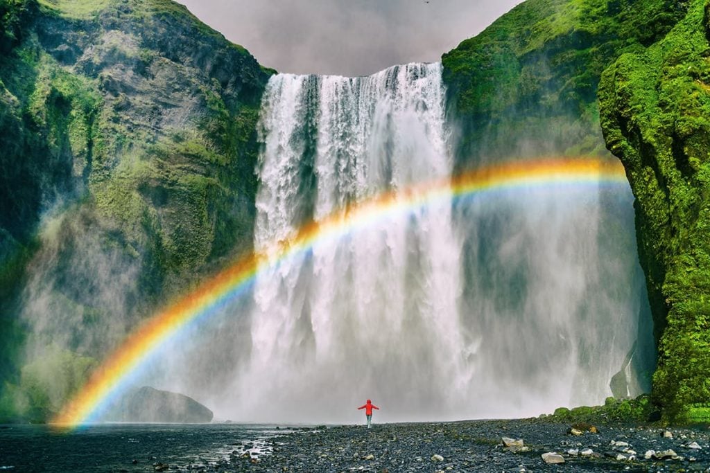 A Waterfall in Iceland With a Rainbow in the Sky